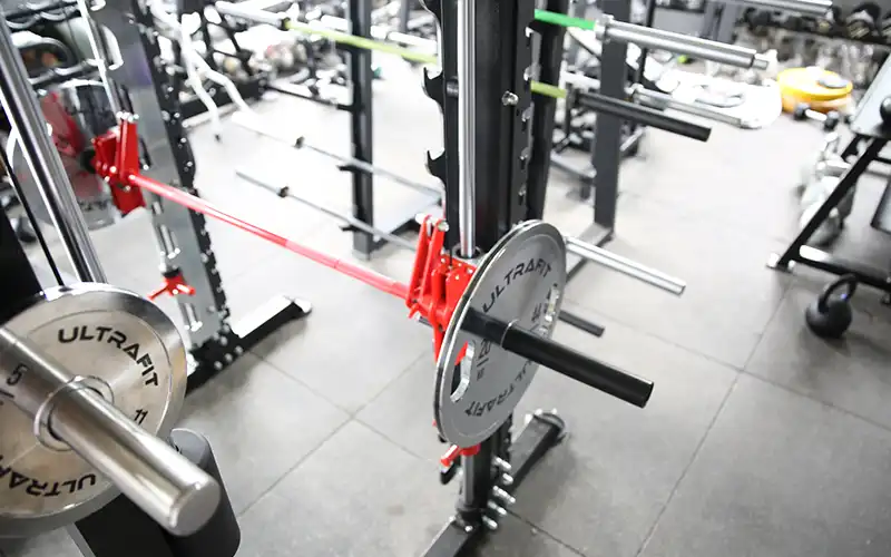 Olympic barbell loaded with weight plates resting on a power rack with J-hooks